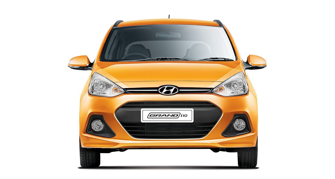 Side-front view of orange Grandi10 with lakeside view at night