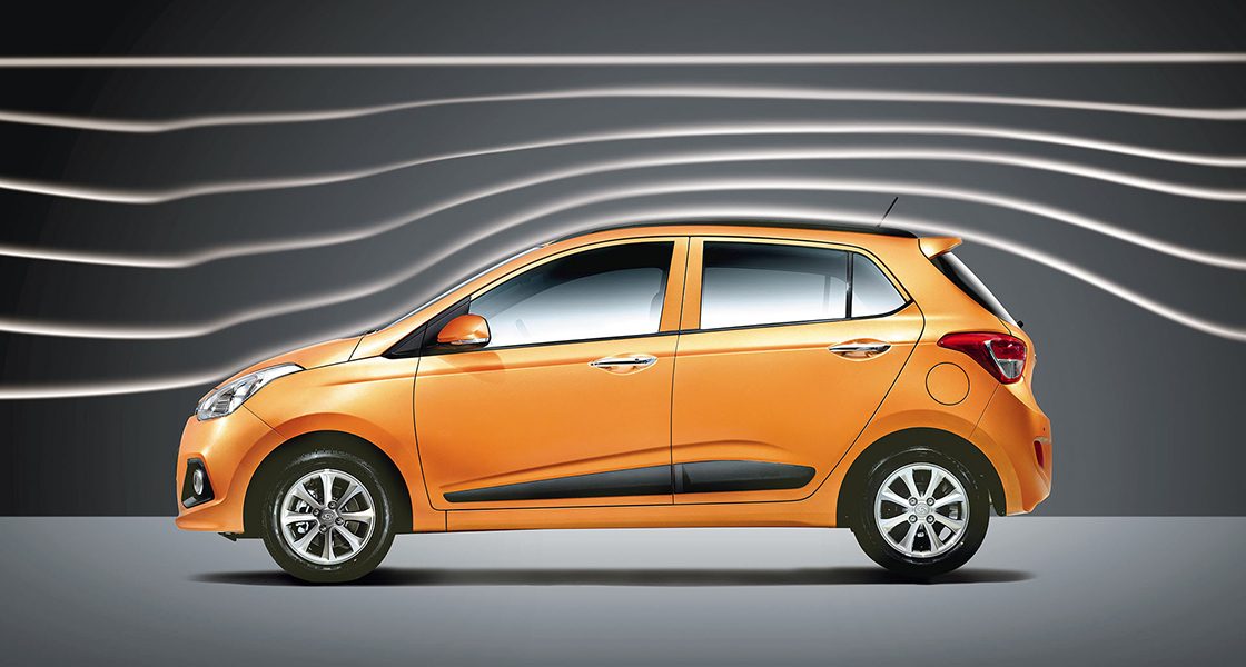 Side-front view of orange Grandi10 with lakeside view at night