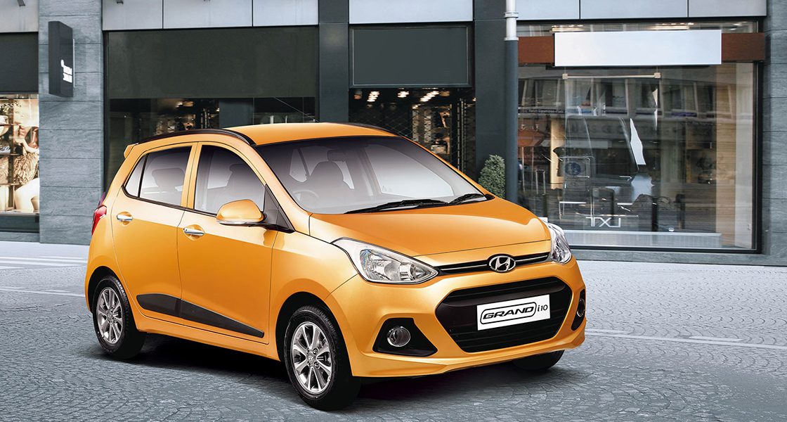 Side-front view of orange Grandi10 with lakeside view at night